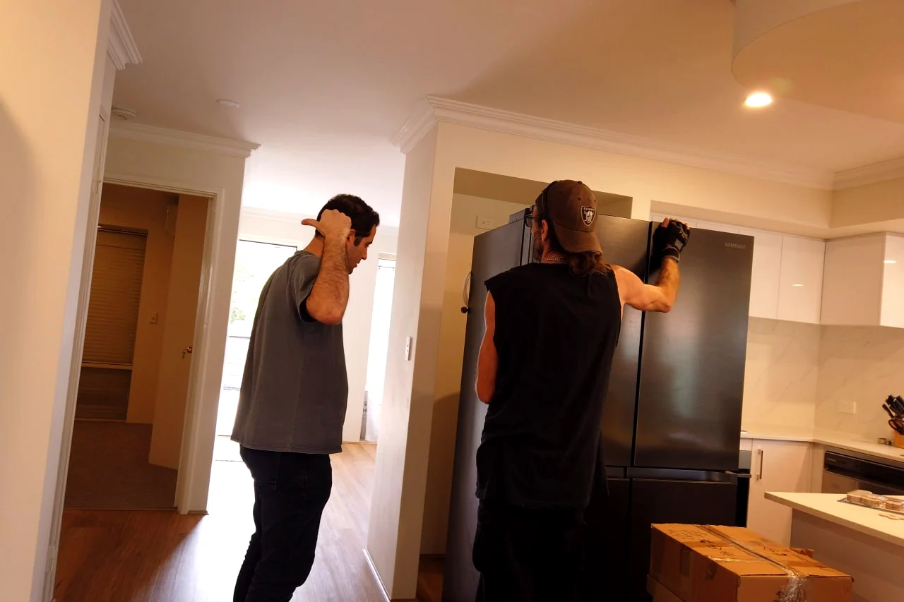 Furniture Removalists Perth movers shifting a heavy fridge into place inside a Perth home