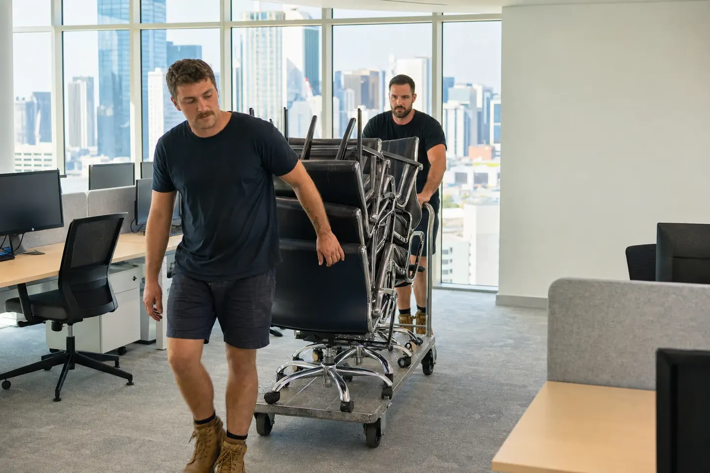 Perth commercial removalist wheeling a trolley of office chairs across an open-plan office