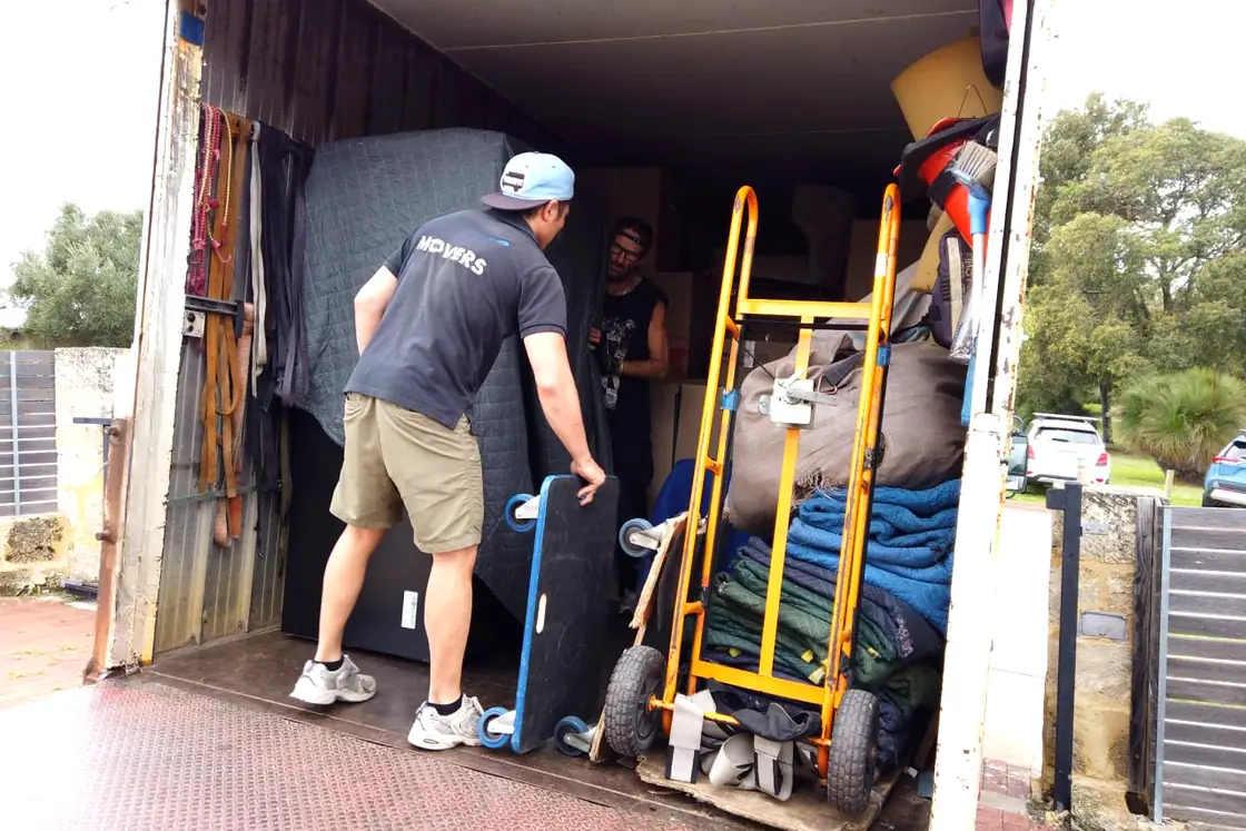 Two Furniture Removalists Perth movers loading a blanket-wrapped mattress into the truck
